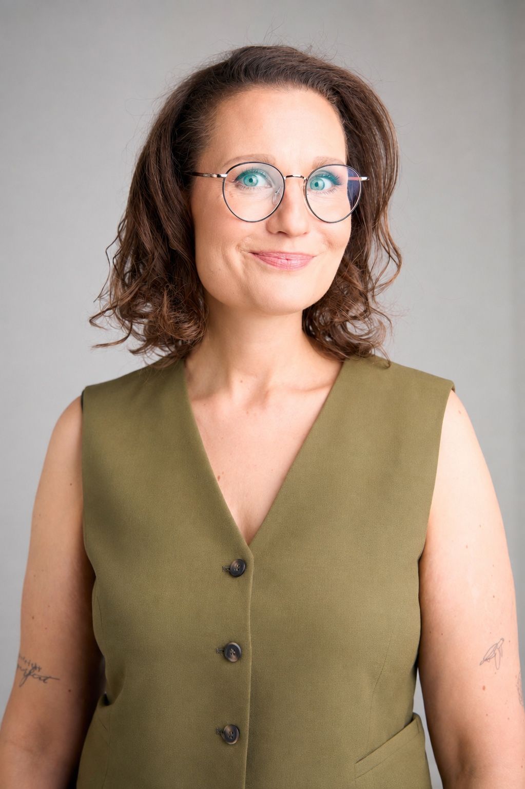 Johanna Schneider, lächelnd, in olivgrüner Weste vor hellem Hintergrund